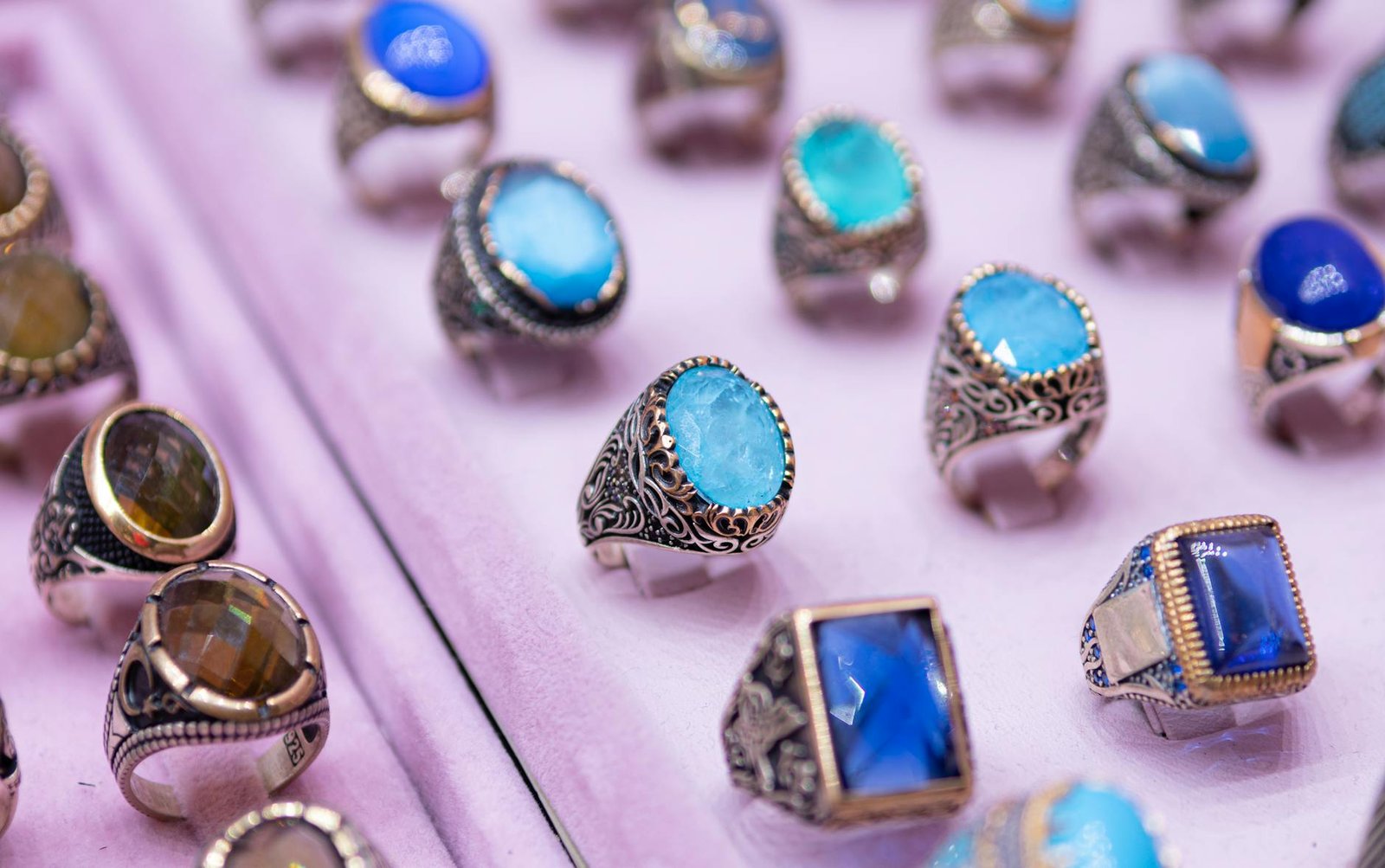 Close-up of beautifully crafted gemstone rings set in intricate silver designs on a soft background.