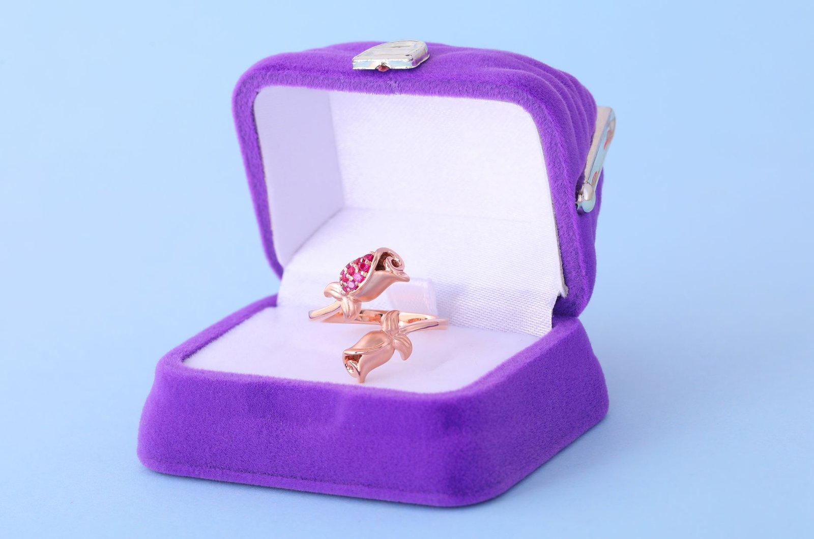 A close-up of an elegant rose gold bird-shaped ring in a luxurious purple ring box.