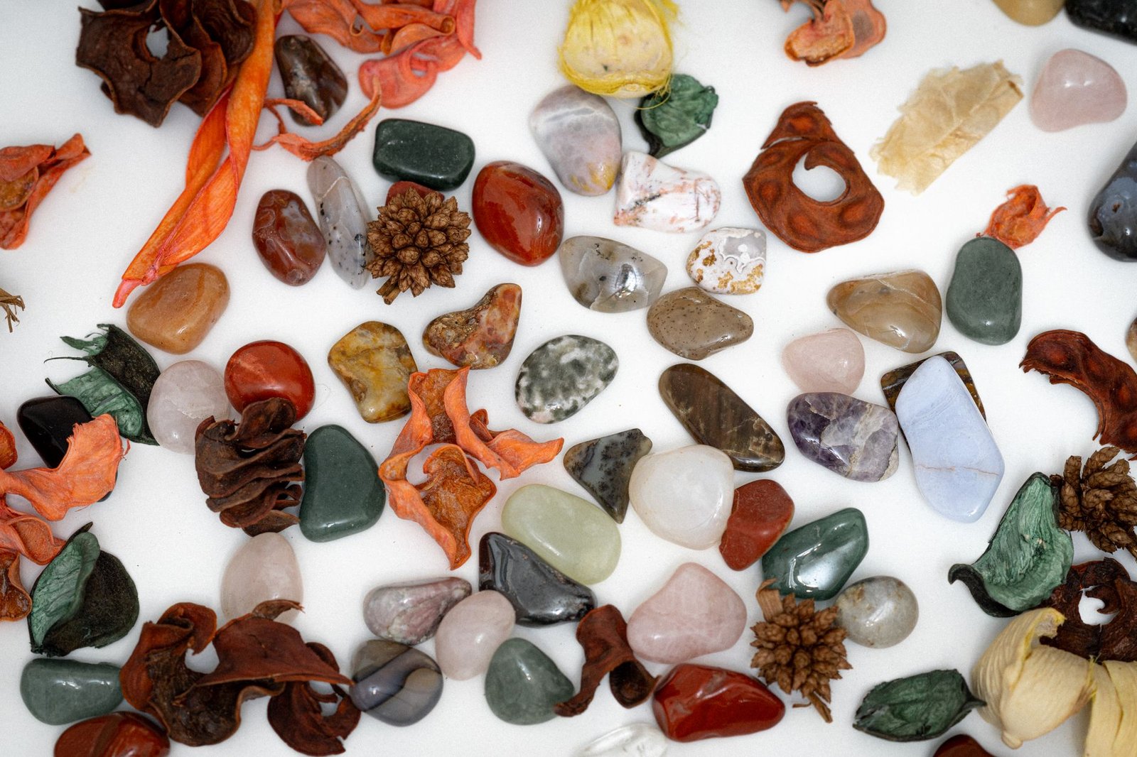 A vibrant collection of polished stones and natural elements laid on a white surface, showcasing earthy tones and textures.